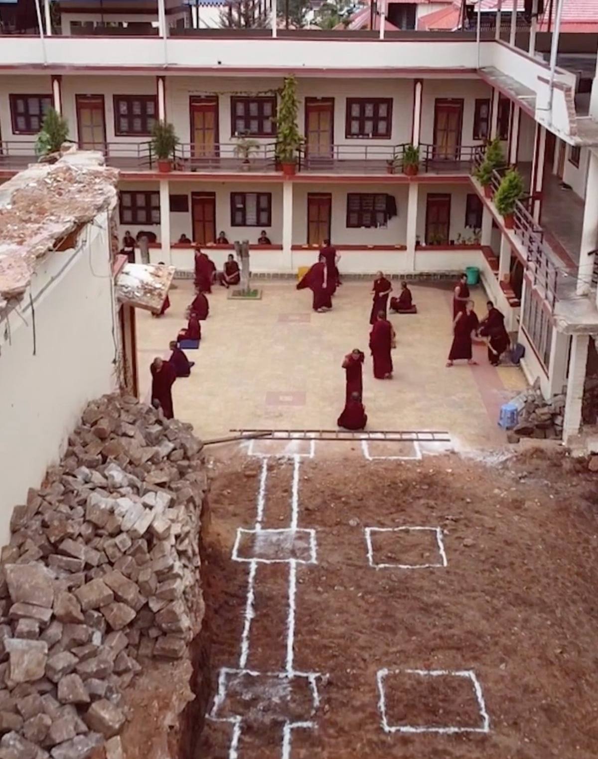 An aerial view of monks debating philosophy in a monastery courtyard