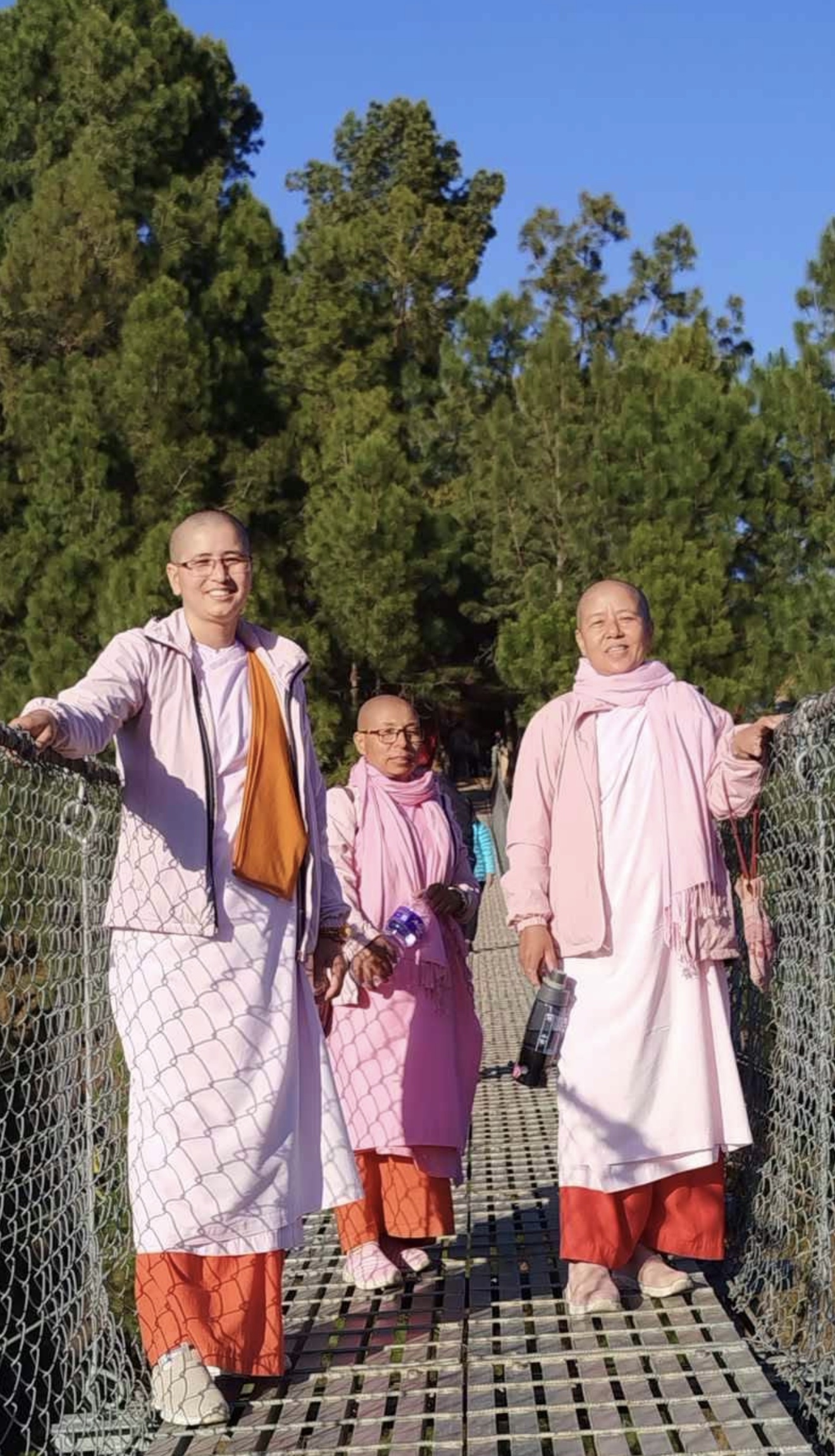Three nuns on a bridge beneath the trees