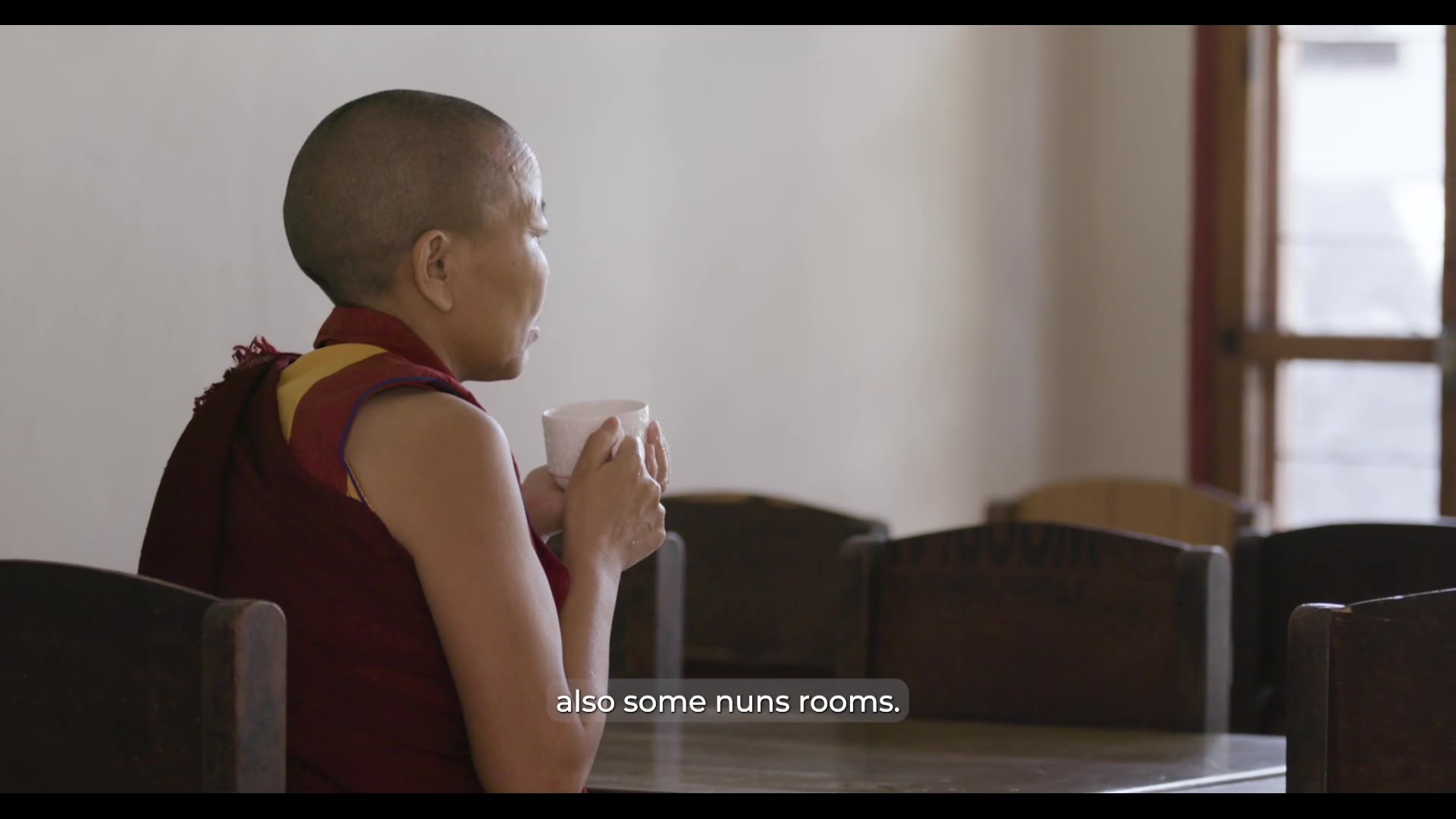 A nun holding a teacup beside a window — still from Rise of the Geshe-Ma