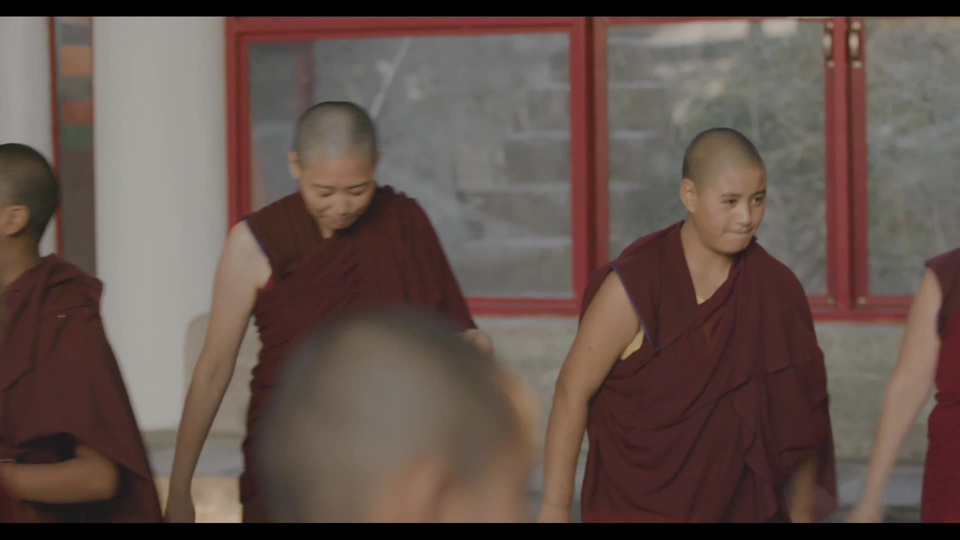 Nuns gathering beside red-framed windows — still from Rise of the Geshe-Ma