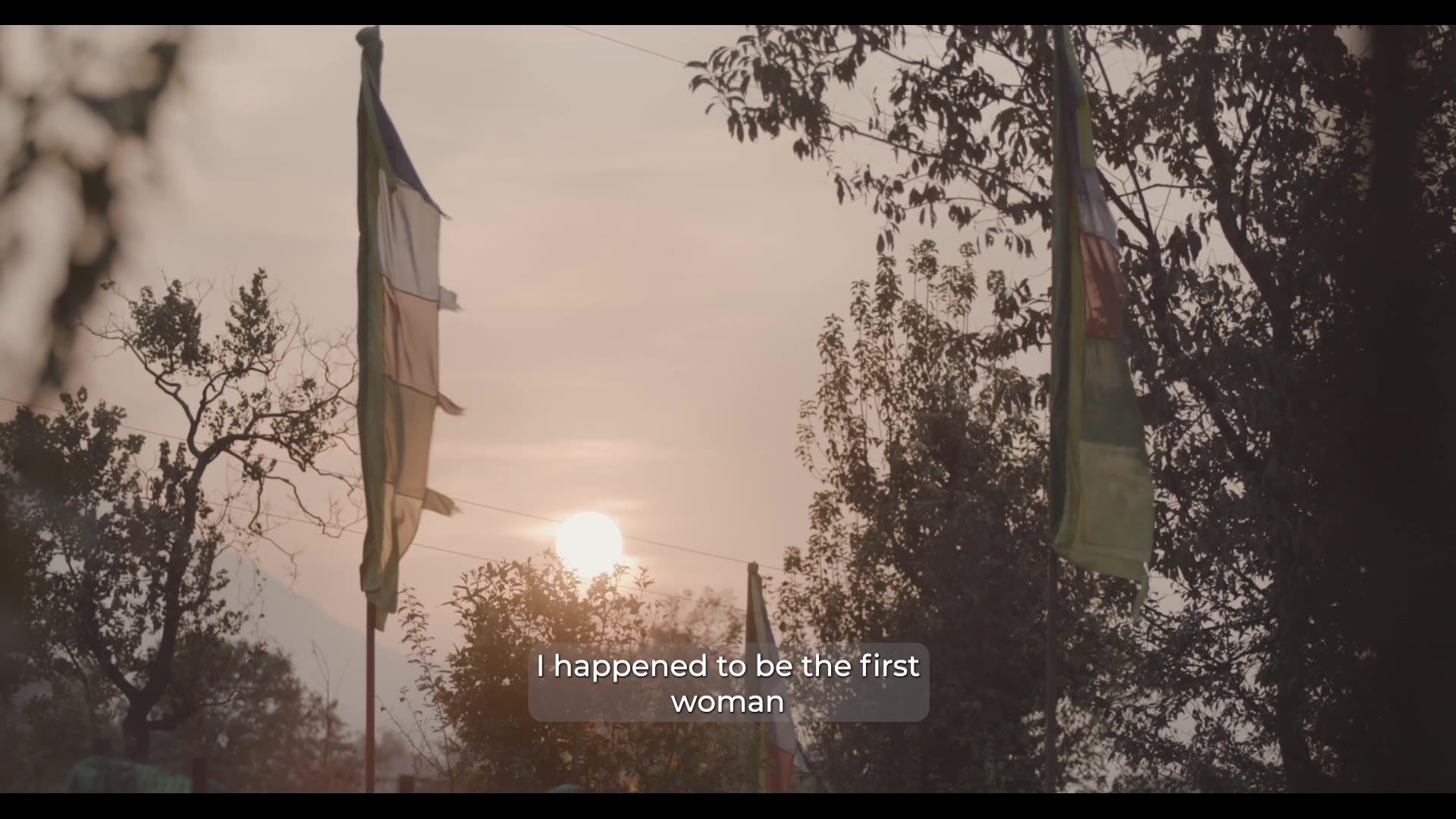 Prayer flags and trees in the evening light — still from Rise of the Geshe-Ma