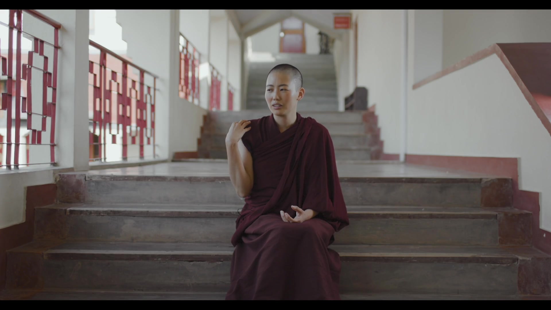 A nun speaking on monastery steps in Rise of the Geshe-Ma