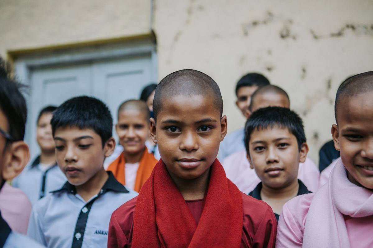 A young monk-student in a red scarf among classmates at the Anandakuthi School, Nepal, The Maitri Project